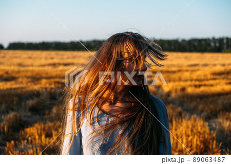 Peaceful woman with long hair in blue linen dress spending time in nature on summer day in sunset. Stress and psychological resilience. Spend Time in Nature to Reduce Stress and Anxiety 89063487