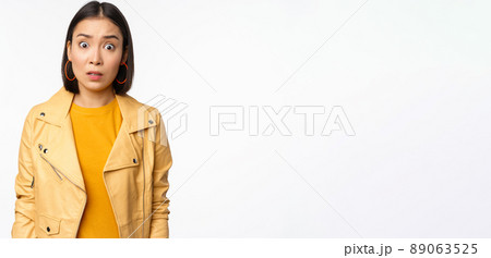 Image of shocked, confused asian woman, staring frustrated and speechless at camera, raising eyebrows and looking concerned, standing over white background Image of shocked, confused asian woman, staring frustrated and speechless at camera, raising eyebrows and looking concerned, standing over white background 89063525