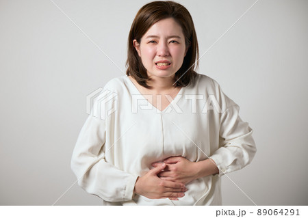 お腹が痛くて手でおさえる若い女性 89064291