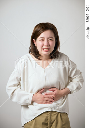 お腹が痛くて手でおさえる若い女性 89064294