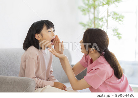 歯科スタッフに歯を見せる女の子 小児歯科 89064436