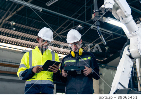 Factory workers working with adept robotic arm in a workshop Factory workers working with adept robotic arm in a workshop 89065451