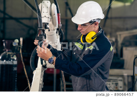 Young factory worker working with adept robotic arm Young factory worker working with adept robotic arm 89066457