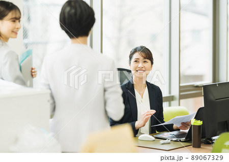オフィスで部下と話をするミドルのキャリアウーマン 89067329