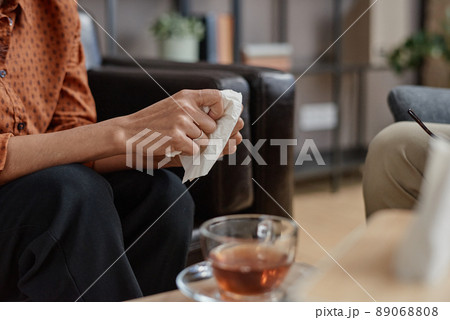 Horizontal medium close-up shot of unrecognizable young adult woman holding paper napkin having psychologist appointment 89068808
