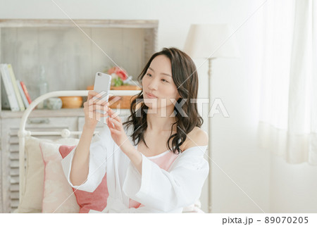 スマホに笑いかける若い女性 スマホに笑いかける若い女性 89070205