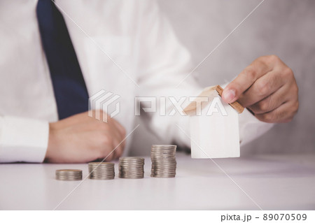 Hands of business man holding model home and stack of coins. Hands of business man holding model home and stack of coins. 89070509