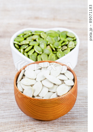 Pumpkin seeds green and unpeeled in wooden bowl. 89071183