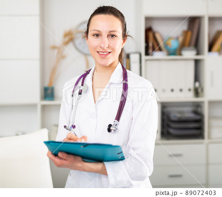 Portrait of friendly female doctor wearing uniform and stethoscope with folder Portrait of friendly female doctor wearing uniform and stethoscope with folder 89072403