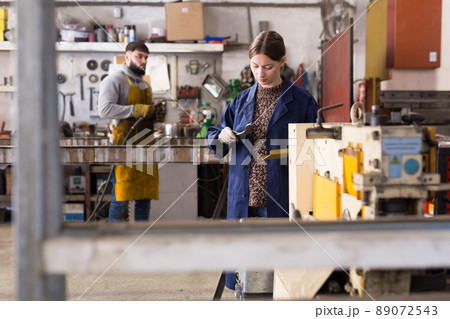 Portrait of female working with drilling machine on metal plate 89072543