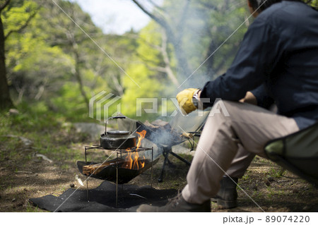 キャンプで焚火をする男性 89074220
