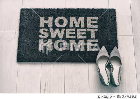 New condo front door mat top view. Modern living business woman high heel shoes on Home Sweet Home entrance doormat. Homeowner moving in concept. background concept. Fashion grey suede high heels 89074292