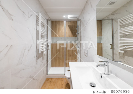 Interior of modern refurbished bathroom with shower and wooden finishing Interior of modern refurbished bathroom with shower and wooden finishing 89076956