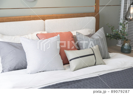 Stylish interior of modern bedroom. White and pastel orange design pillow in cozy bedroom. 89079287