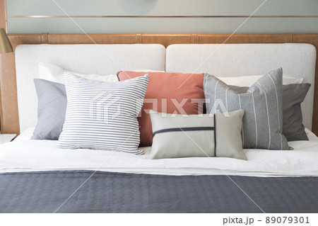 Stylish interior of modern bedroom. White and pastel orange design pillow in cozy bedroom. 89079301