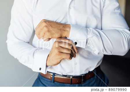 Young businessman in a blue suit straightens a cufflink on a white shirt 89079990