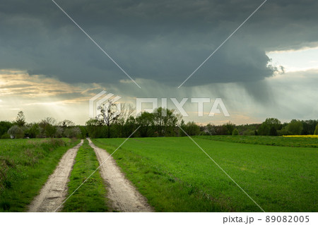 Dark rain cloud over the green field by the road Dark rain cloud over the green field by the road 89082005