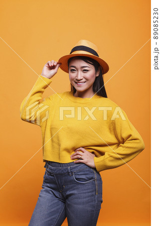 Cheerful charming woman smiling wide with confidence while wearing colorful vivid sweatshirt. Portrait of happy joyful positive asian woman laughing heartily while wearing yellow clothing. 89085230