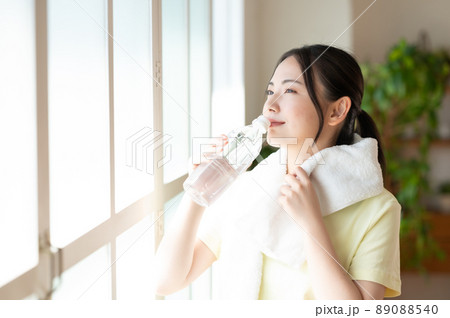 窓際で水分補給する女性 窓際で水分補給する女性 89088540