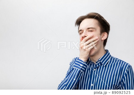 Yawning young man studio shot on gray background 89092525