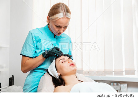 Professional cosmetology in salon. Doctor doing acne treatment using mechanical steel instrument. Concept of cleansing blackhead procedure 89094095