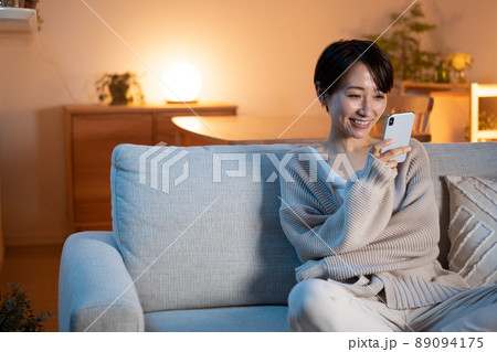 夜に家でリラックスする女性（スマホ・メール・インターネット） 89094175