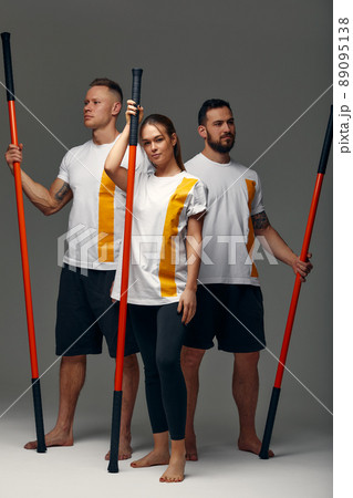 People stand together and practice sticks. Karate masters posing with sticks in the studio together. 89095138