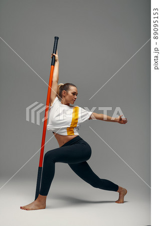 beautiful girl in sports uniform is training kung fu in the studio, fighter athlete, practicing martial arts with a stick 89095153