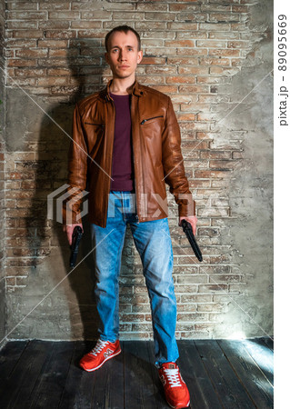 young guy with gun in leather jacket 89095669