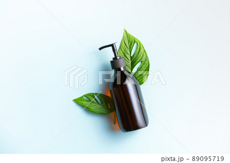 Banner. One cosmetic dark amber glass bottle with green plant on blue background 89095719