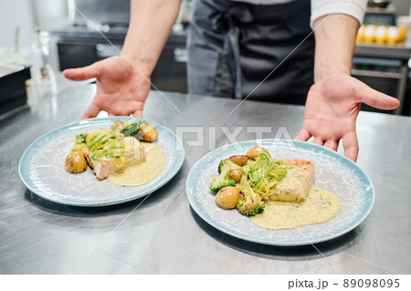 Close-up of chef putting plates with ready dish on kitchen counter for delivery Close-up of chef putting plates with ready dish on kitchen counter for delivery 89098095