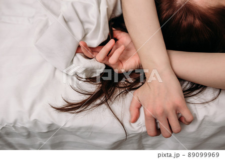 Sensual hands of a woman lying in bed on white sheets 89099969