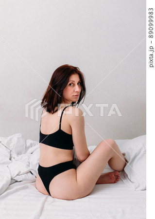 Portrait of a young beautiful brunette lying in bed wearing underwear 89099983
