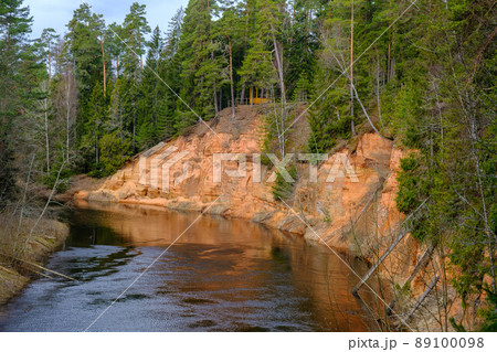 The Echo cliff near river Salaca in Mazsalaca nature park. Beautiful natural formation. A naturally formed cave in the sandstone rock. A river flows along the cave. Devonian period. 89100098