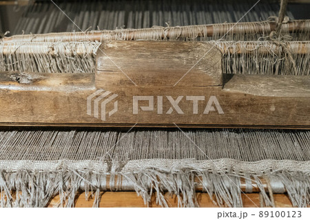 The machine is a hand-made wooden loom with threads for working on the machine. An old loom. The machine is a hand-made wooden loom with threads for working on the machine. An old loom. 89100123