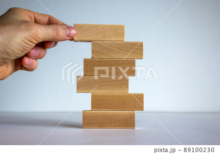 Concept of building success foundation. Men hand put wooden blocks on the stack of wooden blocks. Beautiful white background, copy space. 89100230