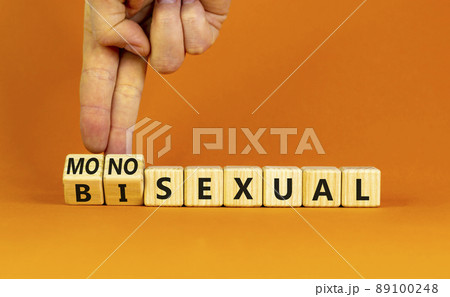 Monosexual or bisexual symbol. Doctor turns wooden cubes and changes the word 'monosexual' to 'bisexual'. Beautiful orange background, copy space. Social, monosexual or bisexual concept. 89100248