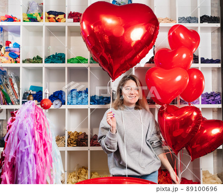 woman with a large red ball of foil in the shape of heart. 89100696