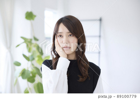 歯が痛くて頬を押さえる女性 歯が痛くて頬を押さえる女性 89100779