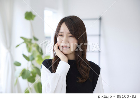 歯が痛くて頬を押さえる女性 89100782