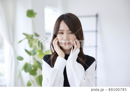 歯が痛くて頬を押さえる女性 89100785