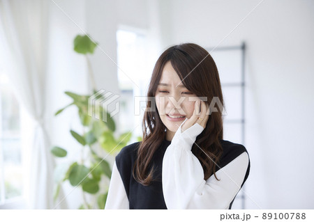 歯が痛くて頬を押さえる女性 89100788