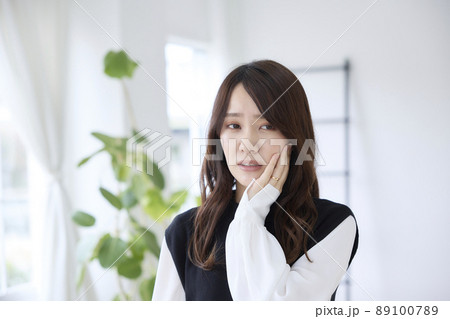 歯が痛くて頬を押さえる女性 歯が痛くて頬を押さえる女性 89100789