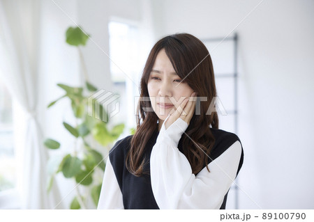 歯が痛くて頬を押さえる女性 歯が痛くて頬を押さえる女性 89100790