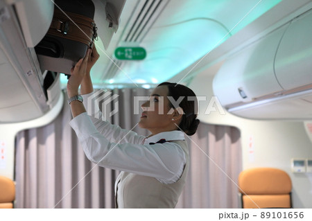 air hostess service on plane , flight attendant checking and closing cabin compartment in airplane air hostess service on plane , flight attendant checking and closing cabin compartment in airplane 89101656