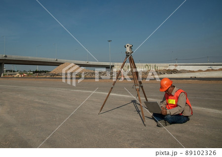 Engineer or surveyor working with theodolite equipment at road construction site. 89102326