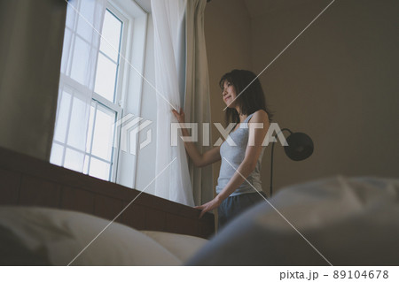 朝、窓の外を眺める女性 89104678