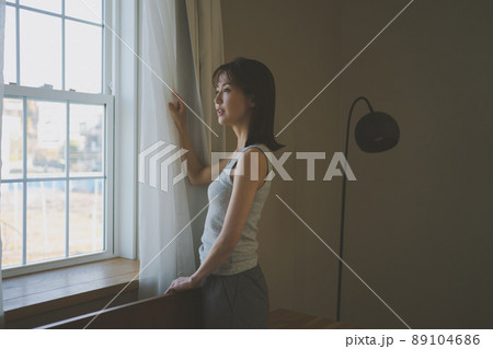 朝、窓の外を眺める女性 89104686