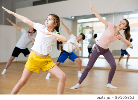 Smiling teenage girl enjoying active dance with family in studio 89105852