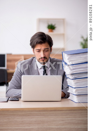 Young male employee unhappy with excessive work in the office Young male employee unhappy with excessive work in the office 89108281